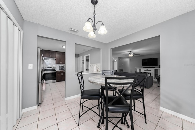 dining space with light tile patterned flooring, ceiling fan with notable chandelier, and a textured ceiling