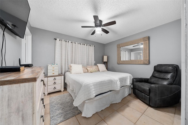 bedroom with ceiling fan, light tile patterned floors, and a textured ceiling