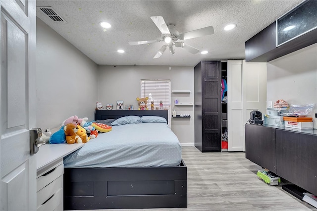 bedroom featuring ceiling fan, a textured ceiling, and light hardwood / wood-style flooring