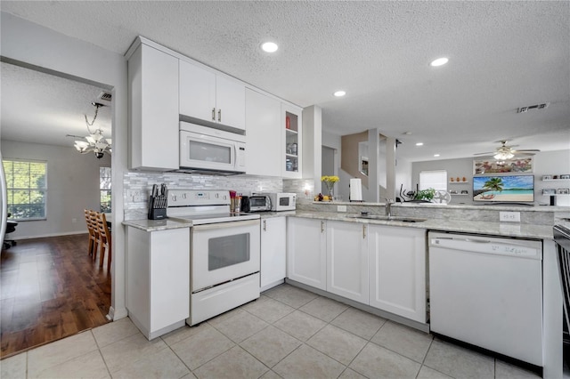 kitchen featuring a textured ceiling, sink, white cabinets, and white appliances