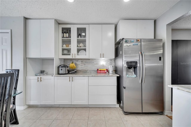 kitchen featuring white cabinets, decorative backsplash, a textured ceiling, light stone counters, and stainless steel fridge with ice dispenser