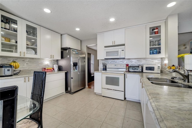 kitchen featuring white appliances, white cabinets, sink, light stone countertops, and light tile patterned floors