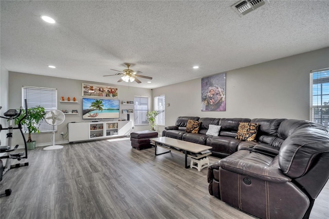 living room featuring ceiling fan, light wood-type flooring, and a textured ceiling