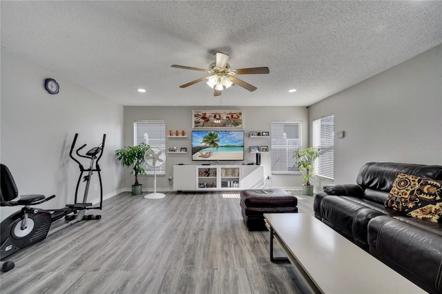 living room featuring ceiling fan, hardwood / wood-style floors, and a textured ceiling