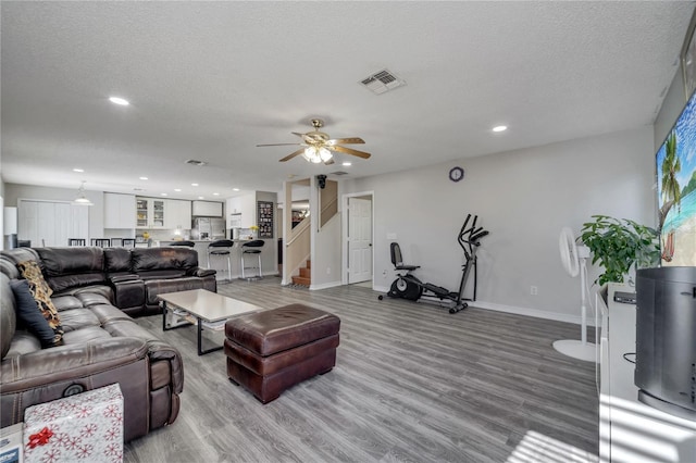 living room with ceiling fan, wood-type flooring, and a textured ceiling