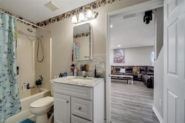 full bathroom featuring backsplash, wood-type flooring, a textured ceiling, toilet, and vanity