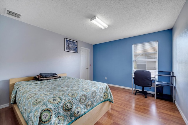 bedroom featuring wood-type flooring and a textured ceiling