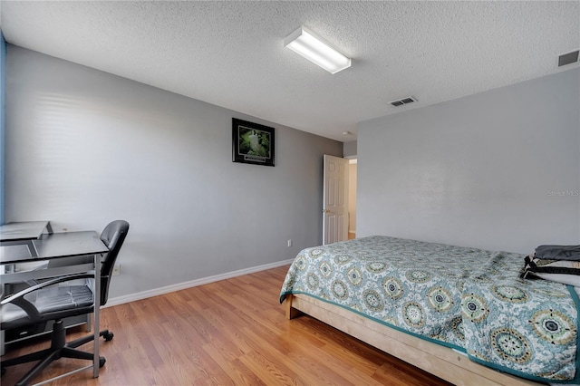 bedroom with light wood-type flooring and a textured ceiling