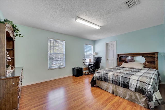 bedroom with light hardwood / wood-style floors and a textured ceiling