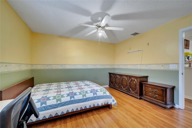 bedroom featuring ceiling fan, light hardwood / wood-style flooring, and a textured ceiling