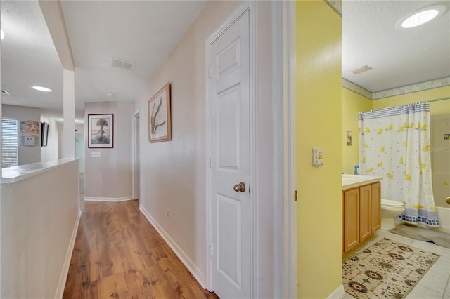 hall featuring a textured ceiling and light hardwood / wood-style flooring