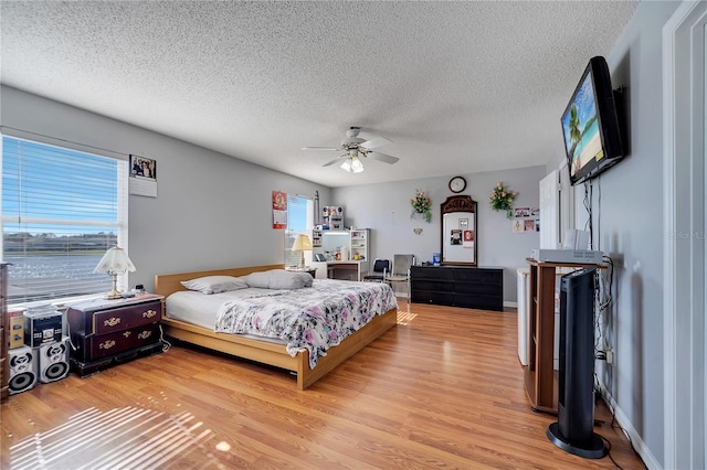 bedroom with ceiling fan, a textured ceiling, and light wood-type flooring