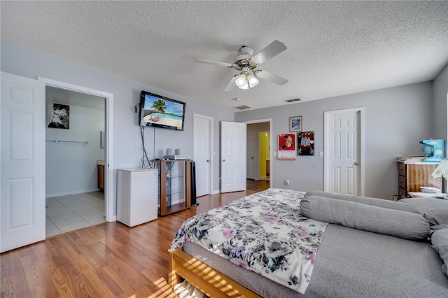 bedroom with ceiling fan, a textured ceiling, and hardwood / wood-style flooring