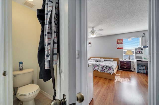 bathroom with hardwood / wood-style floors, a textured ceiling, toilet, and ceiling fan