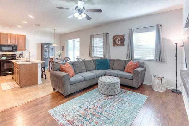 living room featuring ceiling fan, light hardwood / wood-style floors, and sink