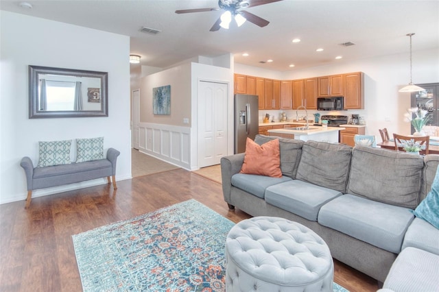 living room featuring dark hardwood / wood-style floors, ceiling fan, and sink