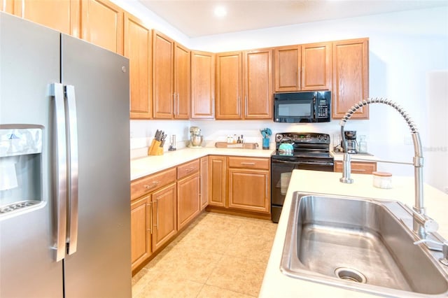 kitchen featuring black appliances, light tile patterned flooring, and sink