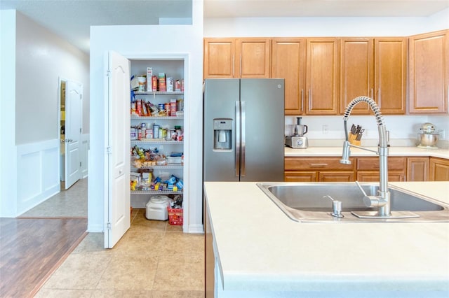 kitchen featuring stainless steel fridge, sink, and light tile patterned flooring