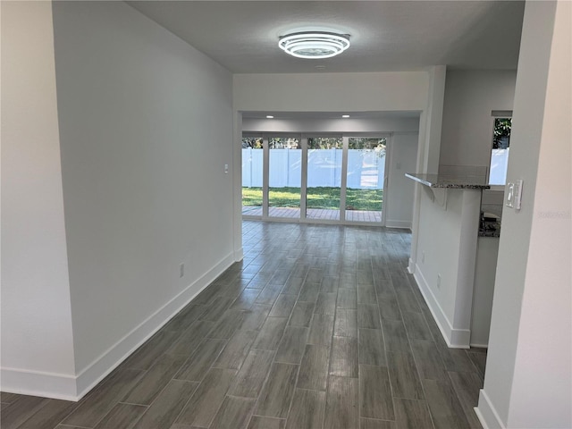 hallway with wood finish floors, baseboards, and recessed lighting