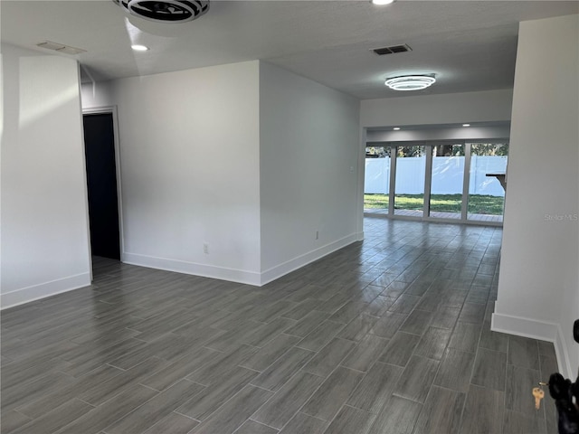 spare room with wood finish floors, visible vents, and baseboards