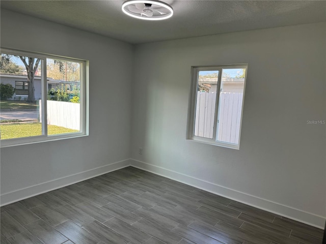 unfurnished room featuring wood tiled floor, plenty of natural light, and baseboards