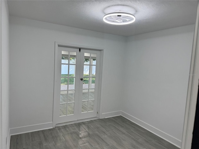 spare room featuring dark wood-type flooring, french doors, a textured ceiling, and baseboards