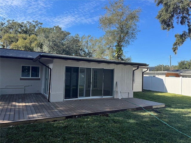 rear view of property featuring a yard, fence, and a wooden deck