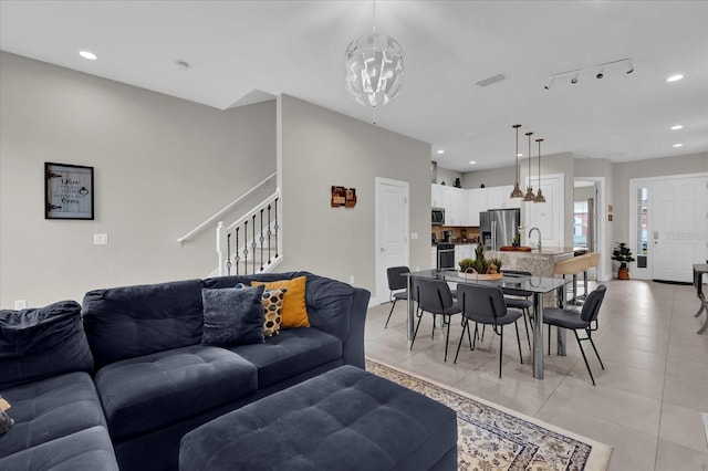 living room with track lighting, light tile patterned floors, a chandelier, and sink