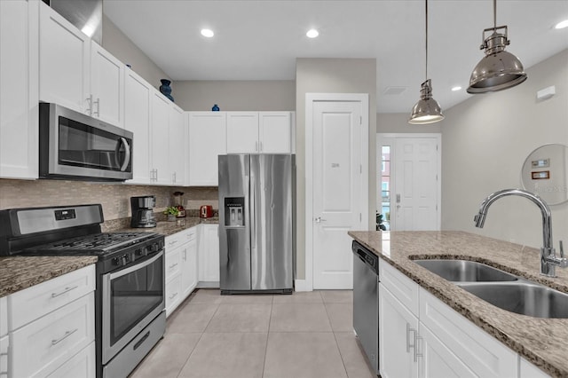 kitchen with white cabinetry, appliances with stainless steel finishes, decorative light fixtures, light stone countertops, and sink