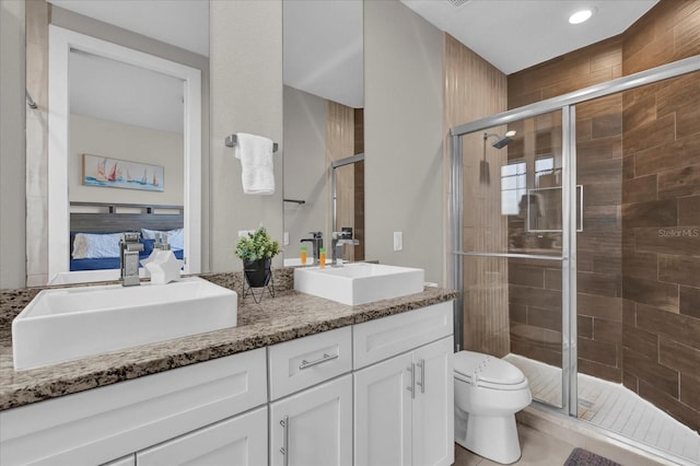 bathroom with toilet, an enclosed shower, and vanity