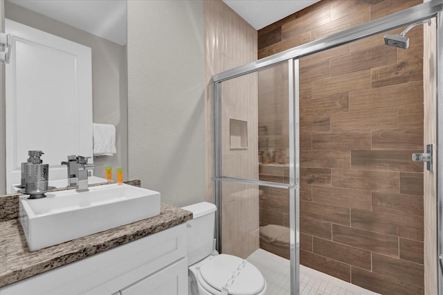 bathroom with toilet, a shower with door, and vanity