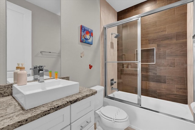 full bathroom featuring toilet, combined bath / shower with glass door, and vanity