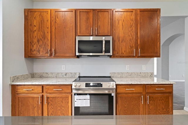 kitchen with appliances with stainless steel finishes, light stone counters, and light tile patterned floors