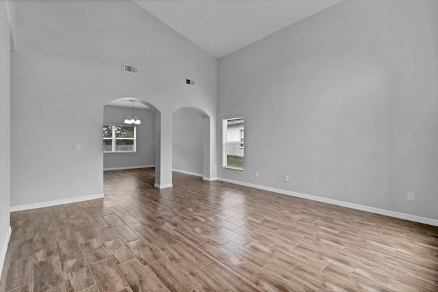 unfurnished living room featuring high vaulted ceiling and an inviting chandelier