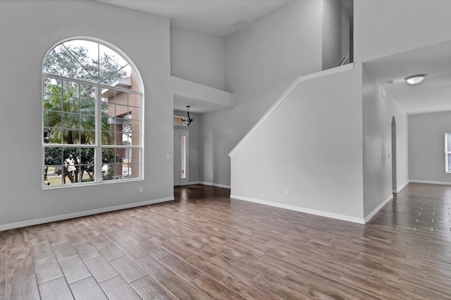 unfurnished living room featuring a notable chandelier and a towering ceiling