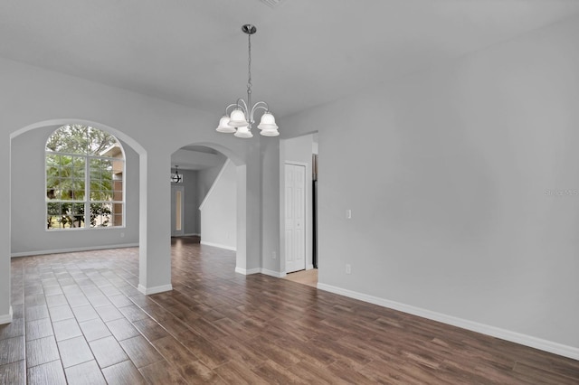 unfurnished room featuring a notable chandelier and hardwood / wood-style flooring