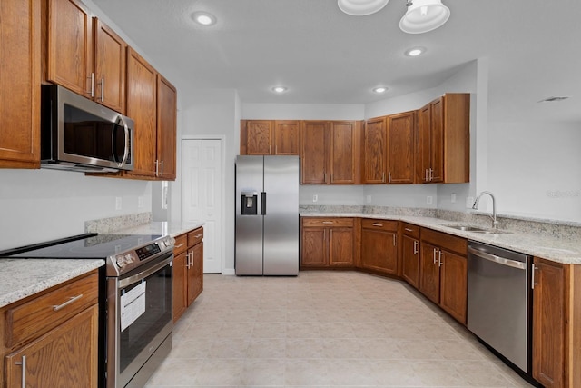 kitchen with light stone countertops, appliances with stainless steel finishes, and sink