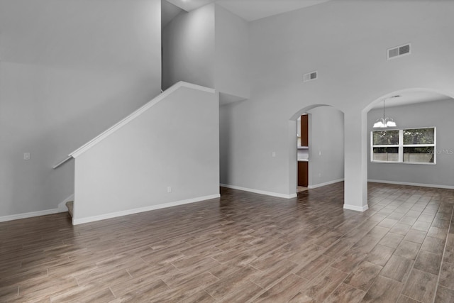 unfurnished living room featuring a high ceiling and an inviting chandelier