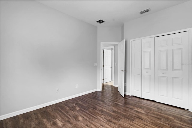 unfurnished bedroom with a closet and dark hardwood / wood-style floors