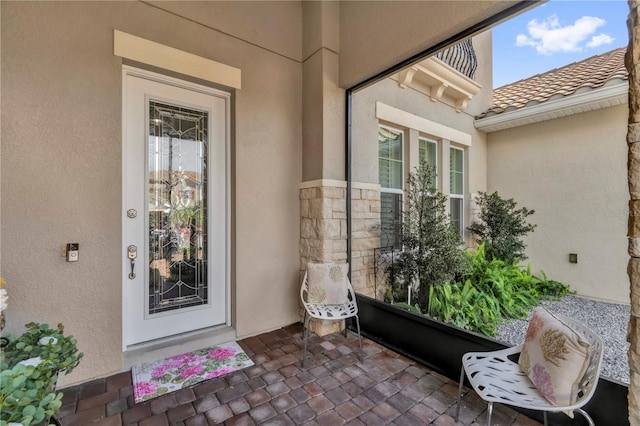 entrance to property featuring a tiled roof and stucco siding