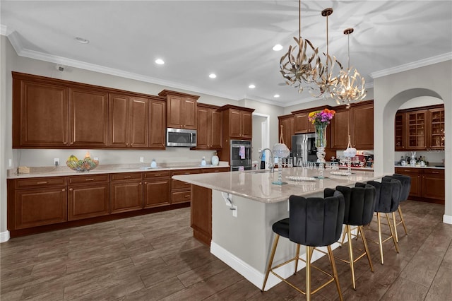 kitchen with stainless steel appliances, crown molding, a large island with sink, a kitchen bar, and pendant lighting