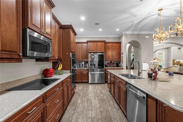 kitchen with crown molding, appliances with stainless steel finishes, wood tiled floor, a sink, and light stone countertops