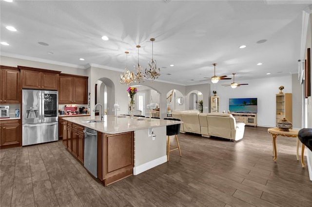 kitchen featuring arched walkways, stainless steel fridge with ice dispenser, brown cabinets, open floor plan, and a sink