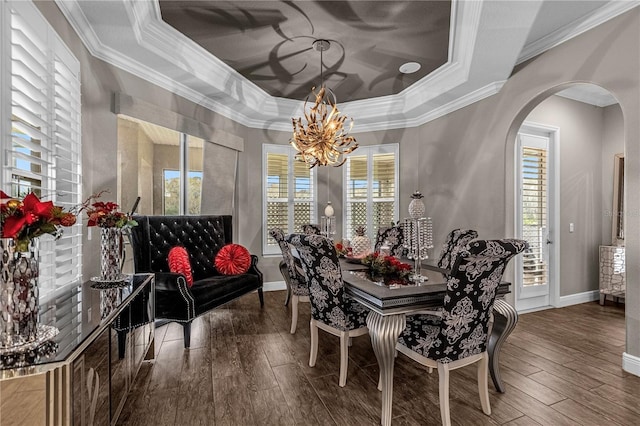 dining area featuring arched walkways, hardwood / wood-style floors, a raised ceiling, and a healthy amount of sunlight