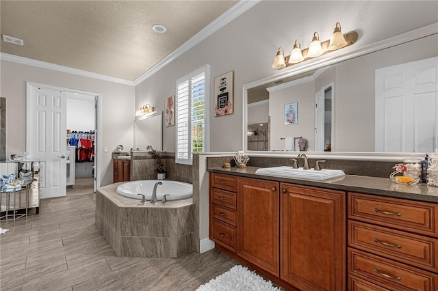 full bathroom featuring visible vents, a garden tub, a walk in closet, crown molding, and vanity