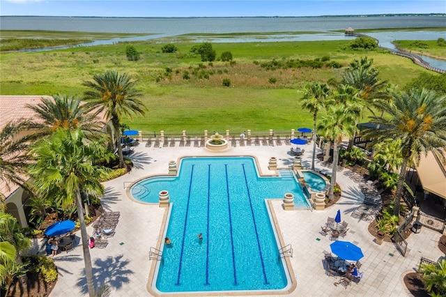 pool with a patio, a water view, and fence