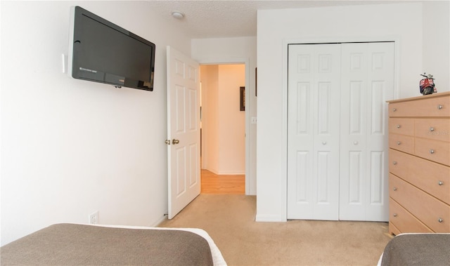 unfurnished bedroom featuring light carpet, a closet, and a textured ceiling