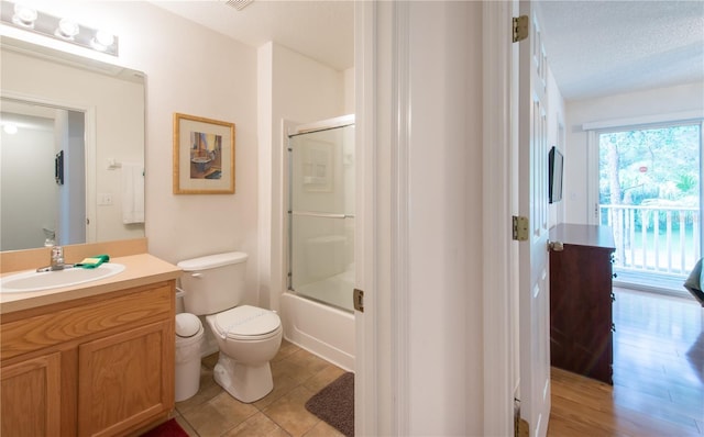 full bathroom featuring a textured ceiling, vanity, enclosed tub / shower combo, tile patterned flooring, and toilet