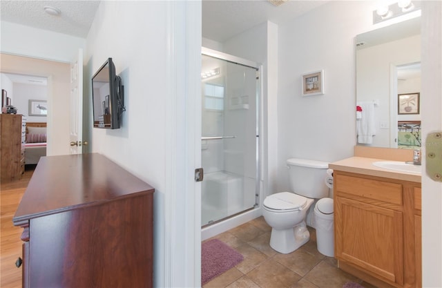 bathroom with vanity, tile patterned flooring, toilet, a textured ceiling, and an enclosed shower