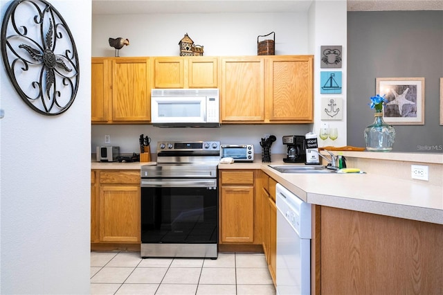 kitchen with light tile patterned floors, white appliances, and sink